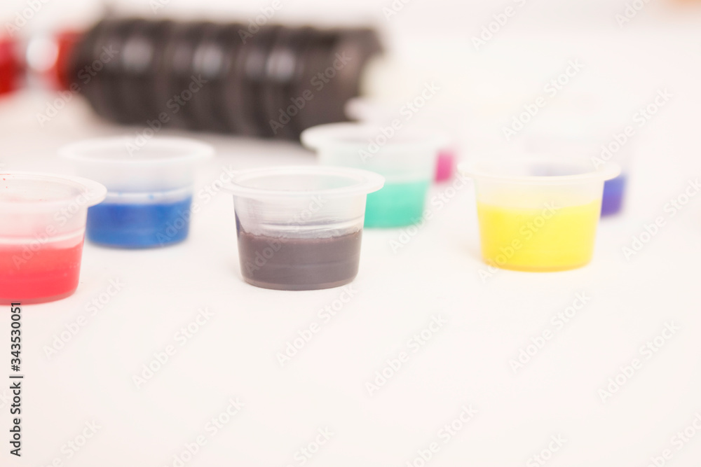 Tattoo paint in plastic jars close, tattoo machine in the background. Tattoo paint in plastic jars close, tattoo machine in the background.