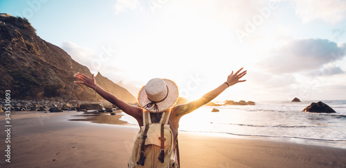 Fotografia Happy woman with arms up enjoy freedom at the beach at sunset