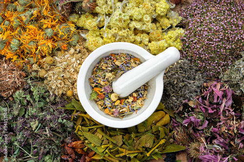 Healing herbs and mortar of medicinal herbs - thyme, coneflower, marigold, daisies, helichrysum flowers, heather, mistletoe. Herbal medicine, top view. photo