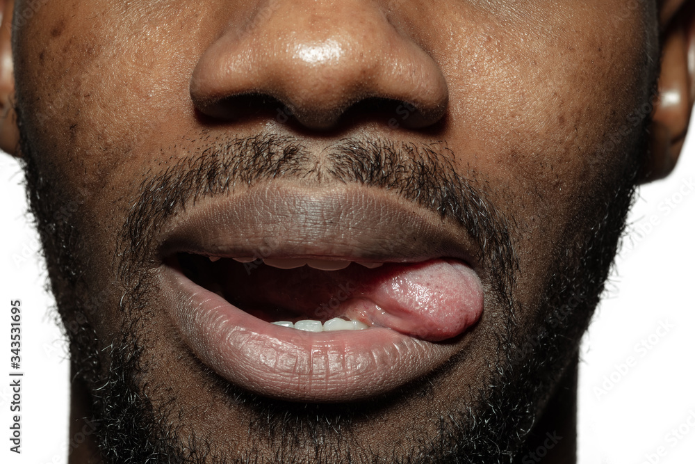 Gremacing. Close up of face of beautiful african-american young man, focus on mouth. Human emotions, facial expression, cosmetology, body and skin care concept. Fun, stick out the tongue. Gremacing. Close up of face of beautiful african-american young man, focus on mouth. Human emotions, facial expression, cosmetology, body and skin care concept. Fun, stick out the tongue.