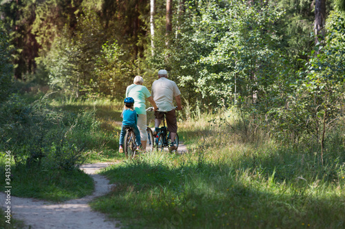 active senior couple with little granddaughter riding bikes in nature © nadezhda1906