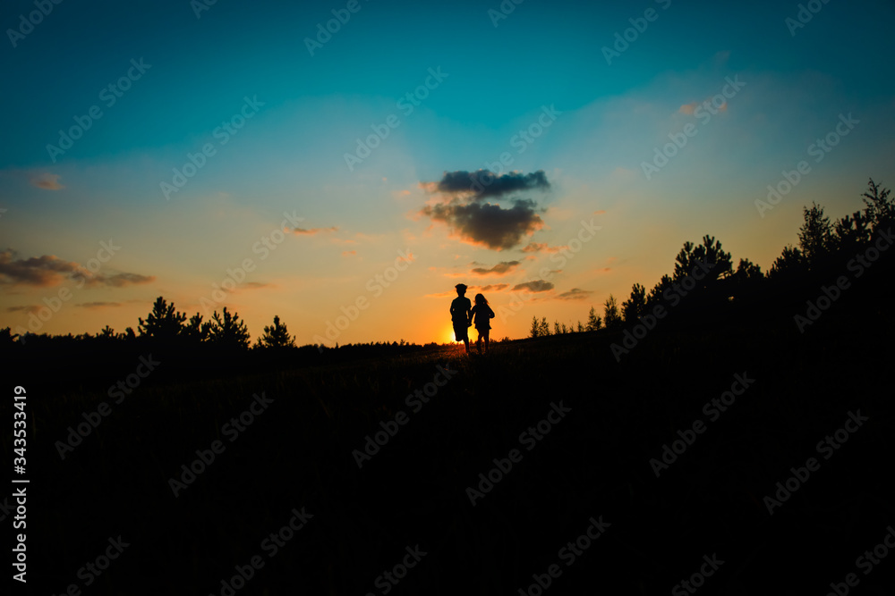 Silhouette of happy boy and girl run at sunset
