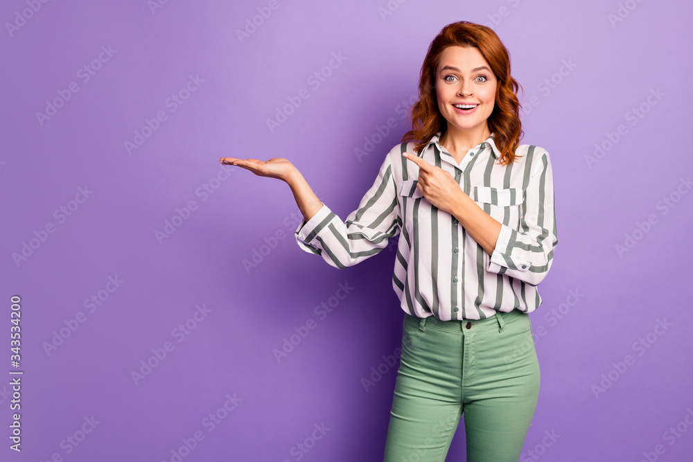 Portrait of amazed surprised woman promoter hold hand present promotion ads point index finger indicate impressed scream wow omg wear stylish clothes isolated over purple color background Portrait of amazed surprised woman promoter hold hand present promotion ads point index finger indicate impressed scream wow omg wear stylish clothes isolated over purple color background