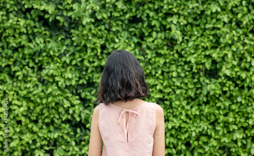 Obraz na płótnie A woman with short hair and pink dressstanding on the background of the Green trees surface. a green natural background. feeling Alone and scared.vintage. Copy space. w salonie