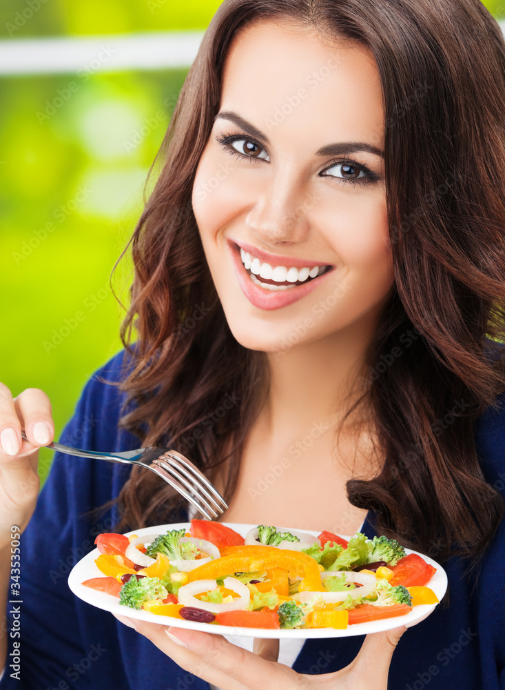Portrait picture of happy smiling young brunette woman with vegetarian vegetable salad