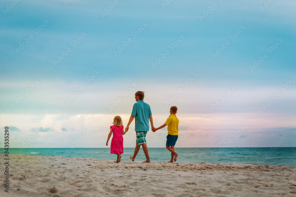 father with son and daugther walking on beach