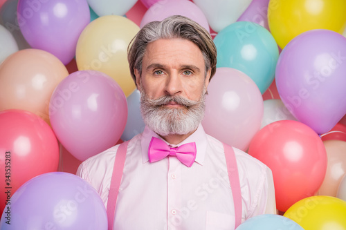 Close-up portrait of his he nice well-dressed attractive serious content imposing grey-haired mature man wearing festal clothes isolated over colorful air balls © deagreez