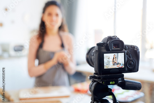 Young woman standing alone in her kitchen shooting bakery tutorial for her food blog channel