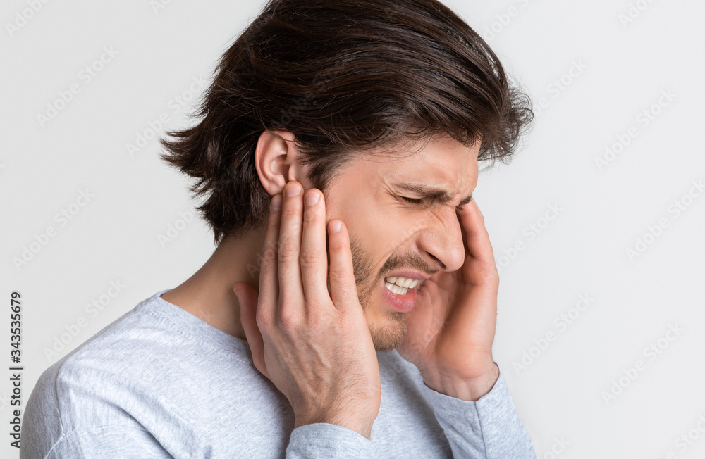 Man with earache is holding sore spot Man with earache is holding sore spot