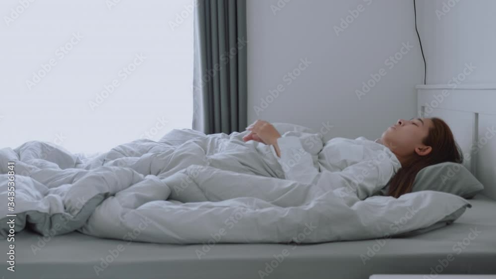Asian woman wake up on bed stretching feeling happy and fresh enjoying in the morning Asian woman wake up on bed stretching feeling happy and fresh enjoying in the morning
