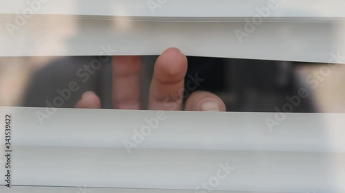 Close-ups of the fingers make a gap from the blinds to let in light into the apartment. Looking from the side is scary because it is afraid of germs. The concept of quarantine, self-isolation, home