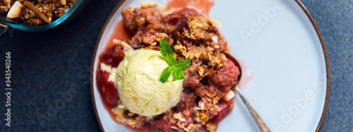 Home cooked Rhubarb and Strawberry crumble from oatmeal and nuts topping and with vanilla ice cream scoops photo