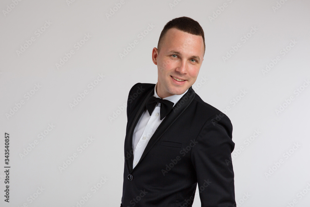 Stylish fashion portraits of a charismatic handsome man in a black tuxedo suit with a bow tie. Emotions, black and white photo, dramatic, close-up. Isolated, white background. Stylish fashion portraits of a charismatic handsome man in a black tuxedo suit with a bow tie. Emotions, black and white photo, dramatic, close-up. Isolated, white background.