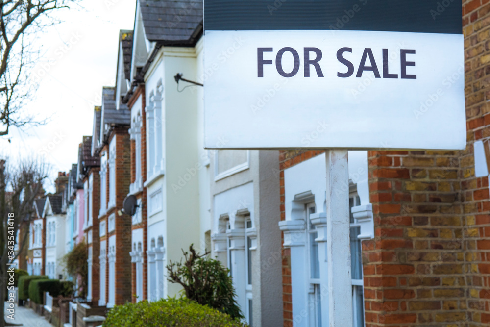 Obraz premium 'For Sale' estate agent sign on street of terraced houses