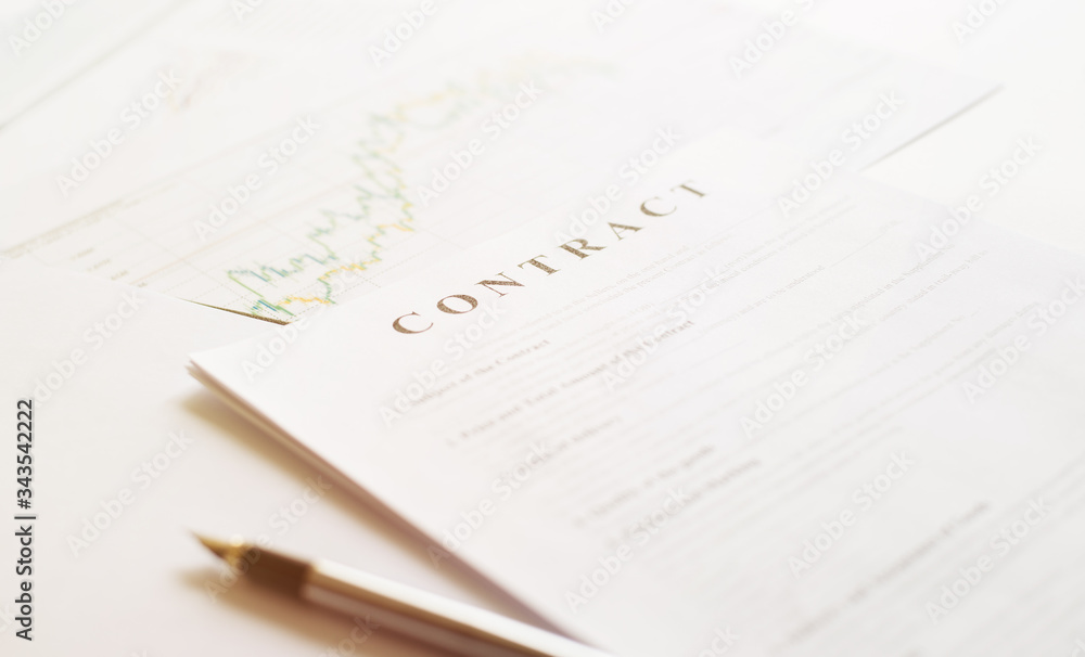 Contract paper and pen on white desk background. Focus on title Contract. Defocused pencil. Contract paper and pen on white desk background. Focus on title Contract. Defocused pencil.