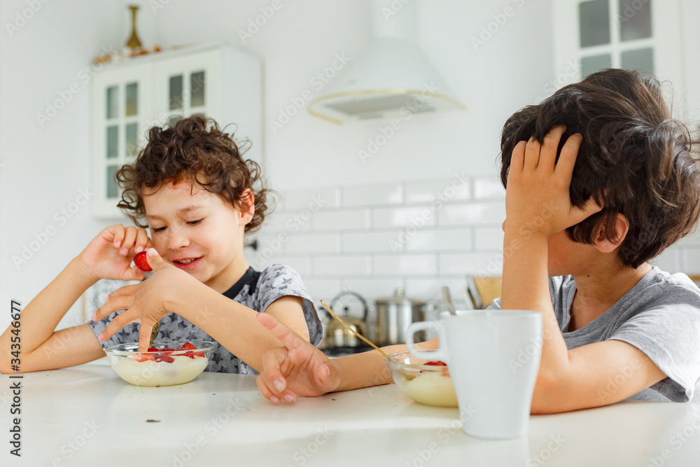 eal brothers have breakfast in the morning in a bright Scandinavian style kitchen with porridge with strawberries eal brothers have breakfast in the morning in a bright Scandinavian style kitchen with porridge with strawberries