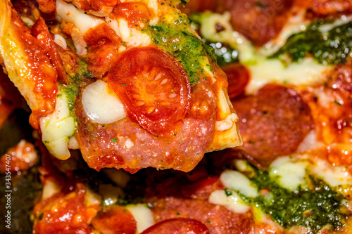 Pizza with salami, tomatoes, pesto and mozzarella. Close up.