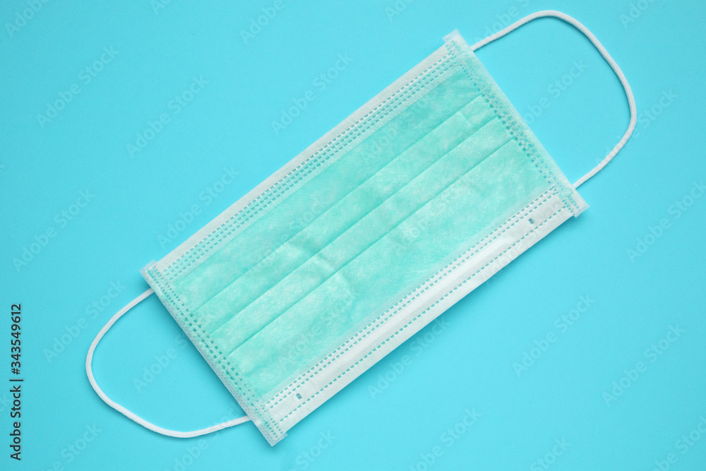 Surgical face mask on blue background protection against COVID-19 coronavirus. Healthcare and medical concept Surgical face mask on blue background protection against COVID-19 coronavirus. Healthcare and medical concept