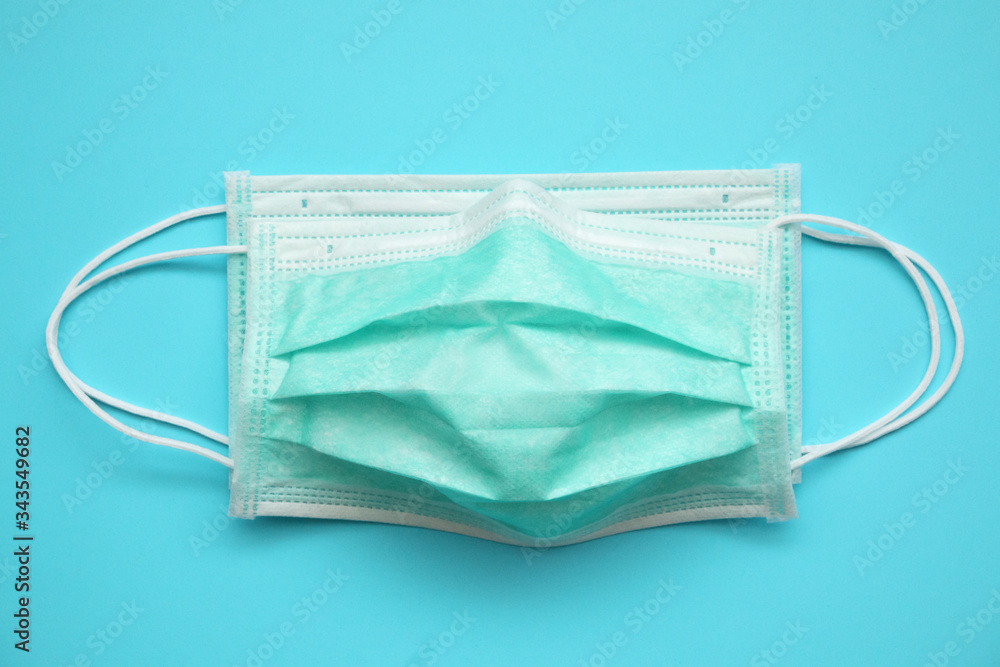 Surgical face mask on blue background protection against COVID-19 coronavirus. Healthcare and medical concept Surgical face mask on blue background protection against COVID-19 coronavirus. Healthcare and medical concept