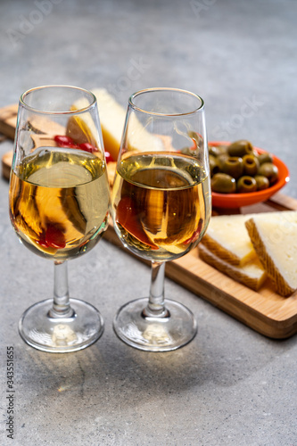 Glasses of dry fino sherry wine served with spanish tapas  manchego cheese  green olives  cheese crackers