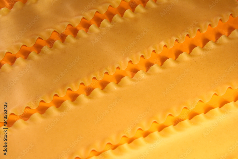 Macaroni on an orange background. The frame is bright. Flour products. The lasagna sheets.