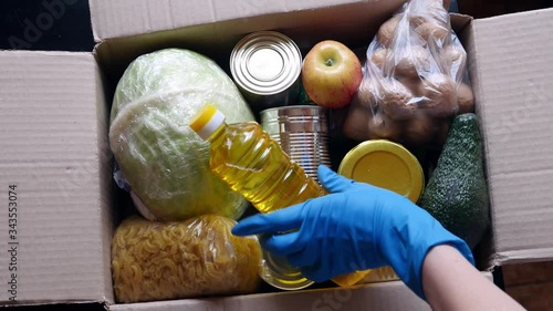Volunteer puts food in a donation box, closeup. Charity and donations. Help during Covid-19 quarantine. Food delivery