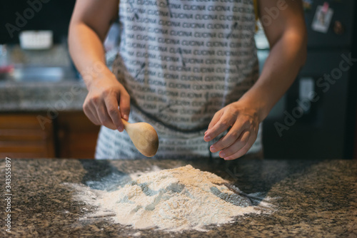 hands ready to prepare dough, flour on the table in rustic kitchen, wooden spoon