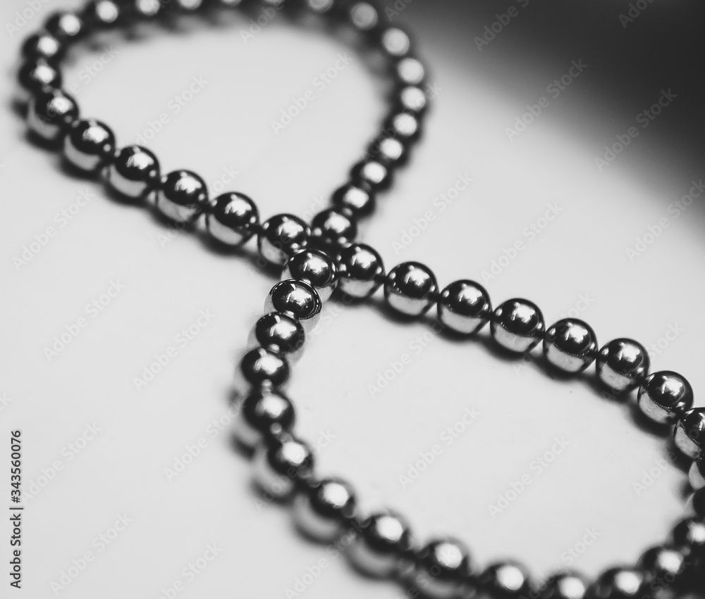 Black beads are stacked in a sign of infinity on a white background. Puzzle and constructor of magnetic balls for adults and children. Stunt. A toy. Accessory. Black beads are stacked in a sign of infinity on a white background. Puzzle and constructor of magnetic balls for adults and children. Stunt. A toy. Accessory.