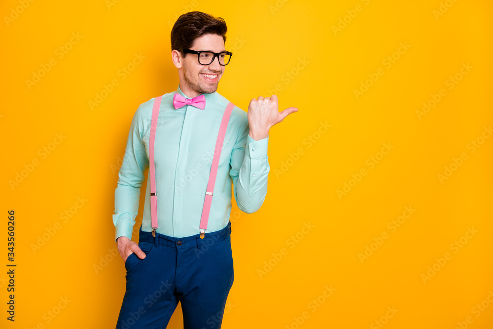 Photo of handsome trend outfit business guy thumb finger directing side  empty space showing novelty product wear specs shirt suspenders bow tie  isolated yellow color background Stock Photo | Adobe Stock