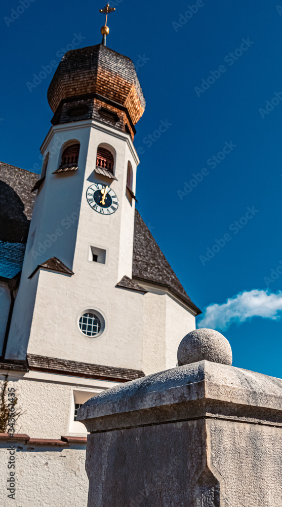 Beautiful stone fence column details with a church in the background near Berchtesgaden, Bavaria, Germany