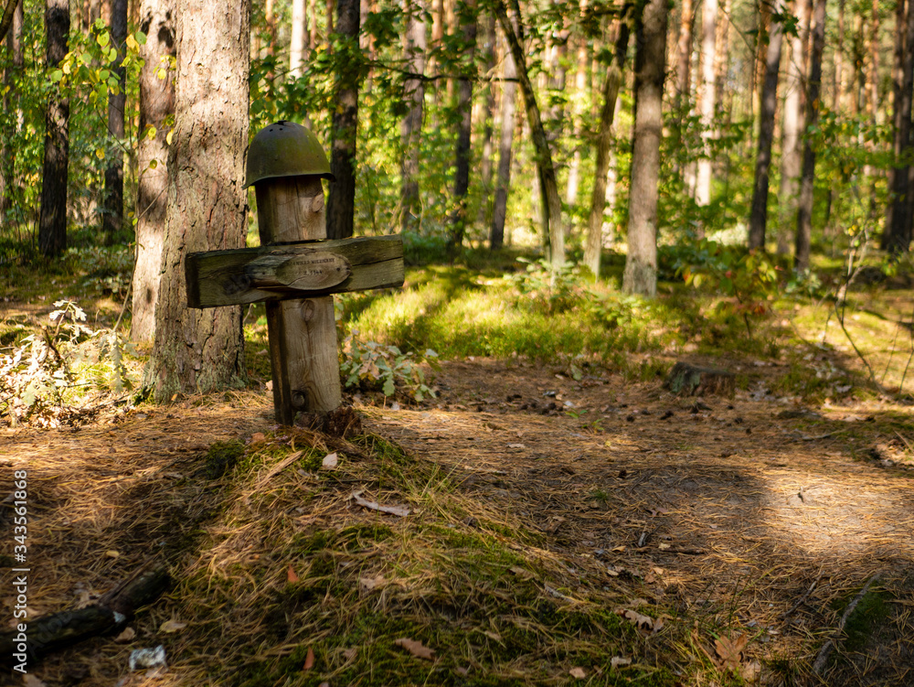 grave from the ground of an unknown soldier in the forest, helmet hanging on the cross grave from the ground of an unknown soldier in the forest, helmet hanging on the cross