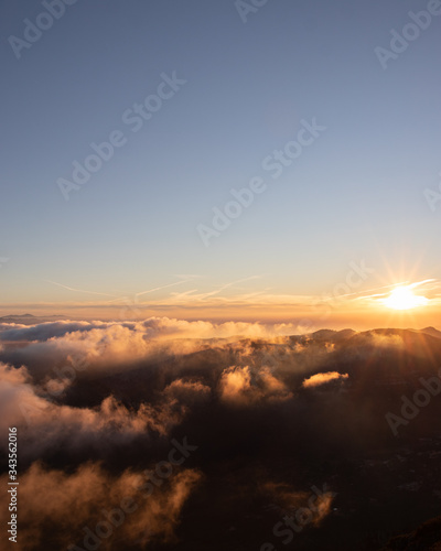 Beautiful mountain peak above the clouds with the sun in the background