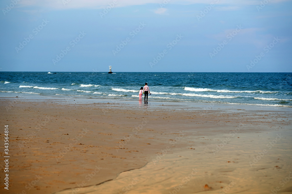 people stand on beach front at coast line on blue sky background