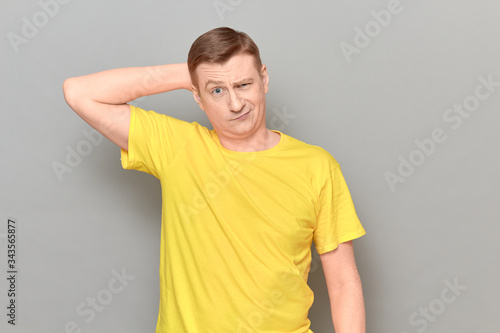 Studio portrait of thoughtful perplexed man holding hand behind head