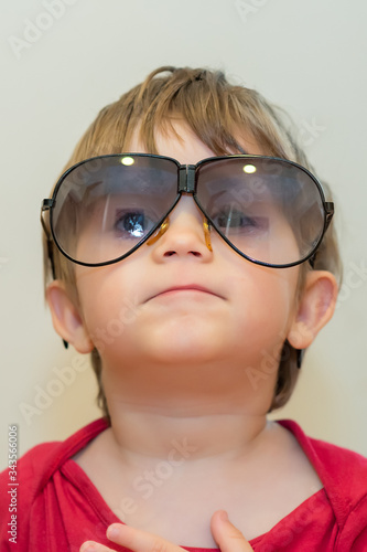 Little boy with big sunglasses. Close up face shot portrait of cute boy wearing huge over sized sun glasses