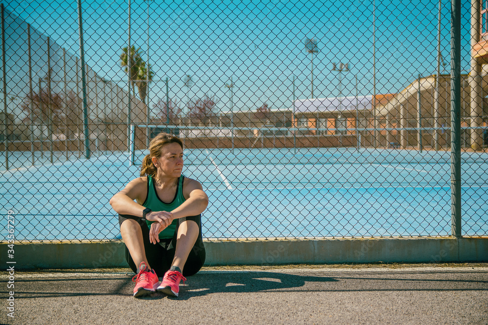 Woman athlete resting sitting on the floor of a sports center. sports