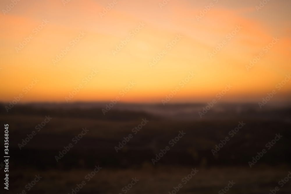 Blurred background of colorful orange sunset in the mountains. Romantic evening in the mountains. Love in the mountains. Countryside Landscape Under Scenic Colorful Sky At Sunset Dawn Sunrise.