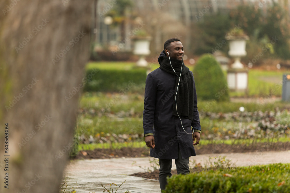 Young Man with Earphones Smiling in Autumnal Park