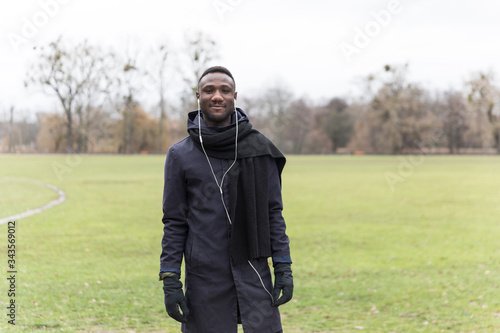 Handsome Black Man with Earphones in Park During Autumn Smiling