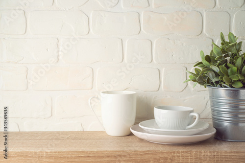 Kitchen background with dishware, cup, plate and plant on wooden shelf