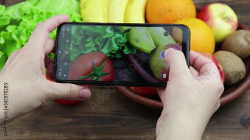 girl's hands take photos of fresh fruits and vegetables on her smartphone. food photograp