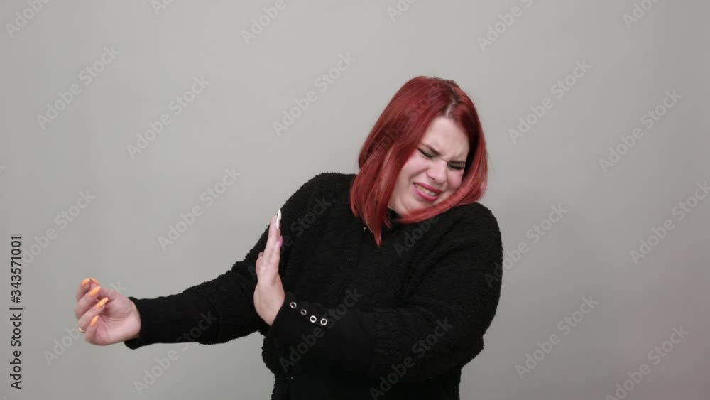 Young redhead fat lady in black sweater on grey background, dissenting woman holds the palms of her hands in front of as sign of protest Young redhead fat lady in black sweater on grey background, dissenting woman holds the palms of her hands in front of as sign of protest