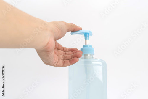 Asian mand hand holds a gel alcohol pump bottle and ready to pushes on it. It's an isolated object on the white clear screen in studio light.