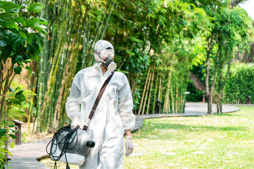 Professional specialist walking and observating around the outdoor garden to prepare spraying sanitizer liquid solution for kill Coronavirus (COVID-19).