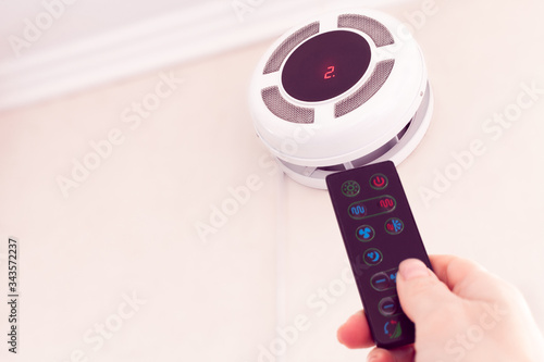 female hand by remote control turning on recuperator for fresh indoor air quality