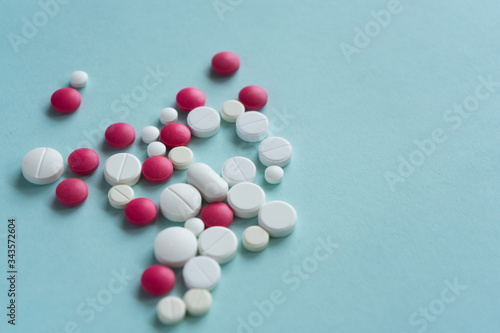 Placer of multi-colored, white and pink tablets, pills of various shapes, on blue background. pharmacies and pandemic content. Medical concept.