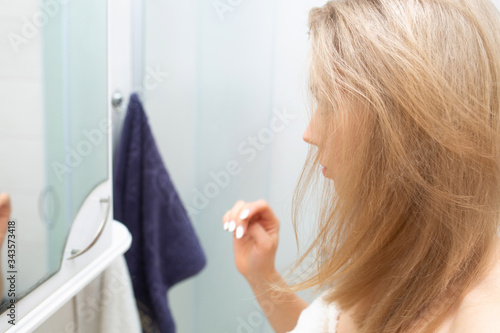 Pretty girl looks in a mirror in a bathroom.
