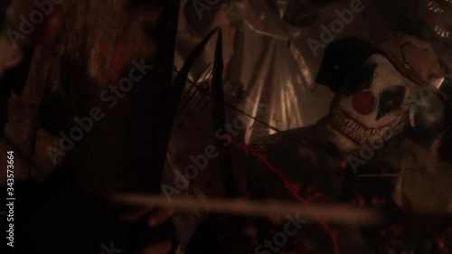 A scarier clown with knife at crude basement with a mirror on the wall