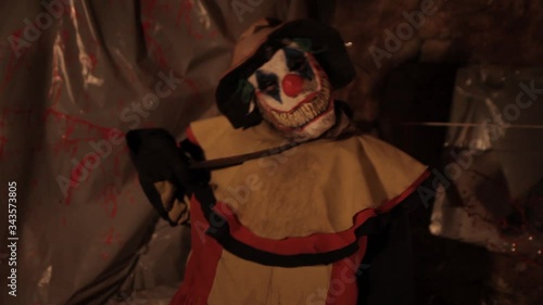 A scarier clown with knife at crude basement with a mirror on the wall