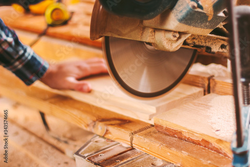 Obraz na płótnie Closeup of professional joiner working with electric circular saw at woodworking workshop